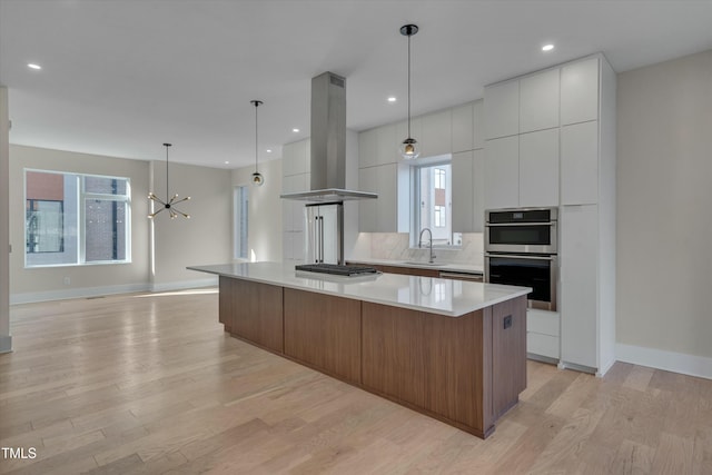 kitchen with a spacious island, island exhaust hood, sink, and white cabinets