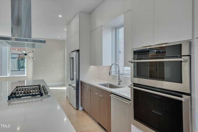 kitchen with sink, island range hood, a wealth of natural light, stainless steel appliances, and white cabinets