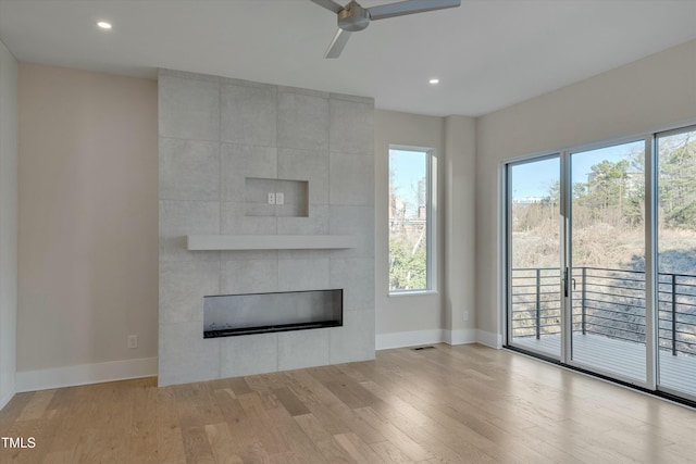 unfurnished living room with ceiling fan, a fireplace, and light hardwood / wood-style floors