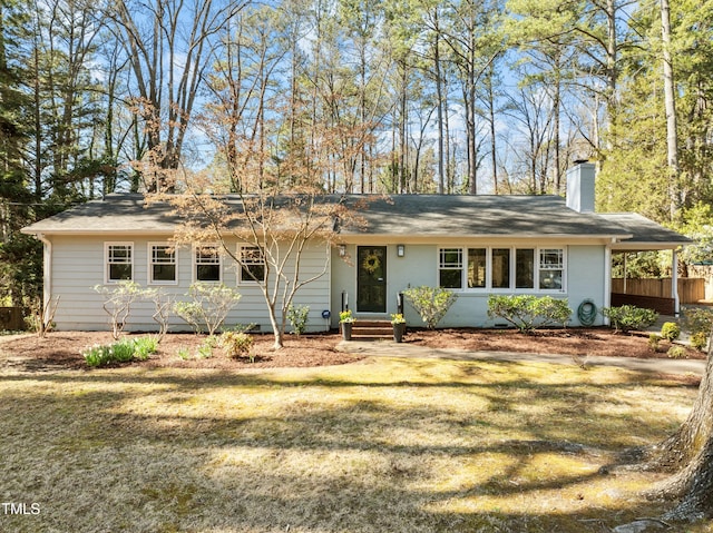 ranch-style home featuring an attached carport, a front yard, and a chimney