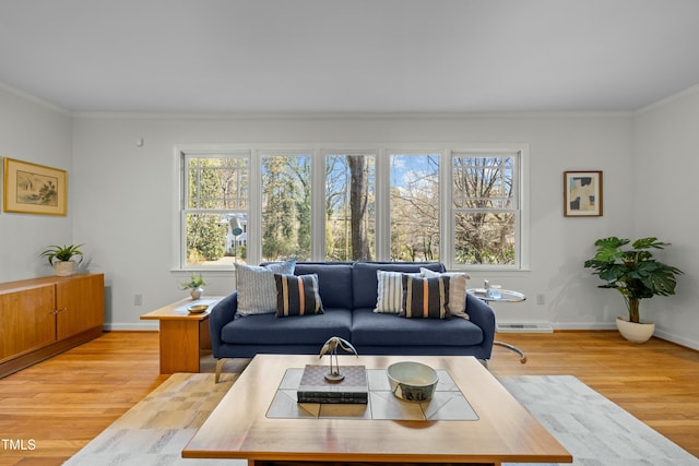 living area with visible vents, baseboards, ornamental molding, and light wood finished floors