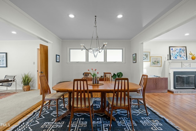 dining room featuring a notable chandelier, wood finished floors, recessed lighting, crown molding, and a brick fireplace