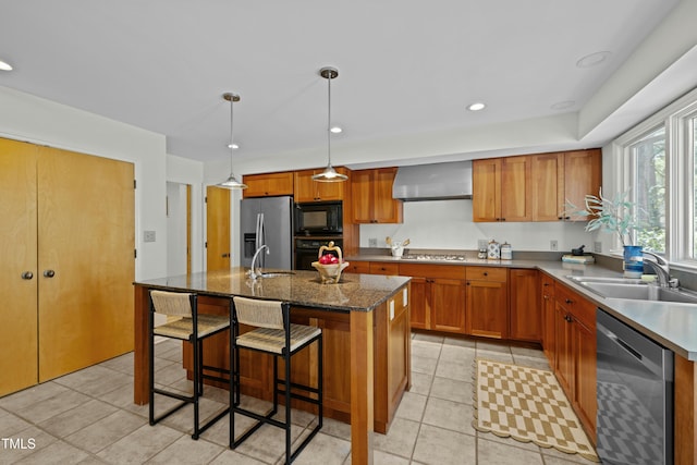 kitchen featuring black appliances, wall chimney range hood, brown cabinets, and a sink