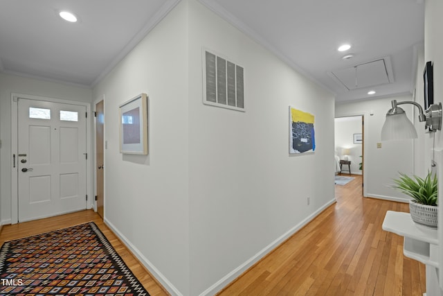 entryway featuring visible vents, baseboards, light wood-style flooring, and ornamental molding