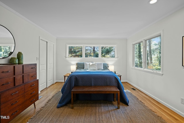 bedroom with crown molding, baseboards, and light wood finished floors