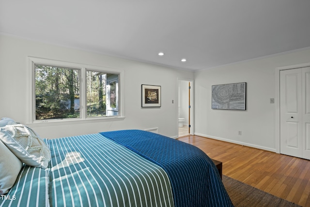 bedroom with wood finished floors, recessed lighting, connected bathroom, crown molding, and baseboards