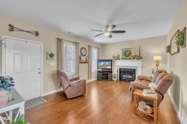 living room featuring ceiling fan, hardwood / wood-style floors, and a fireplace