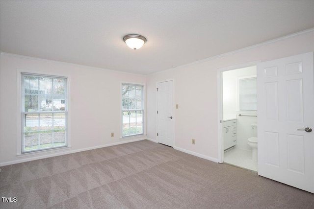 unfurnished bedroom featuring crown molding, connected bathroom, light colored carpet, and a textured ceiling