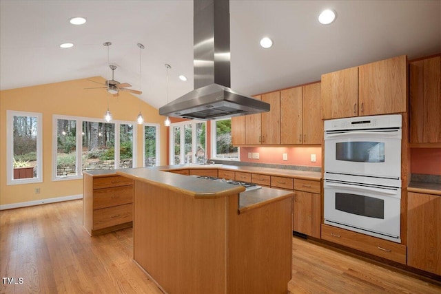 kitchen with a kitchen island, double oven, island exhaust hood, light hardwood / wood-style floors, and gas stovetop