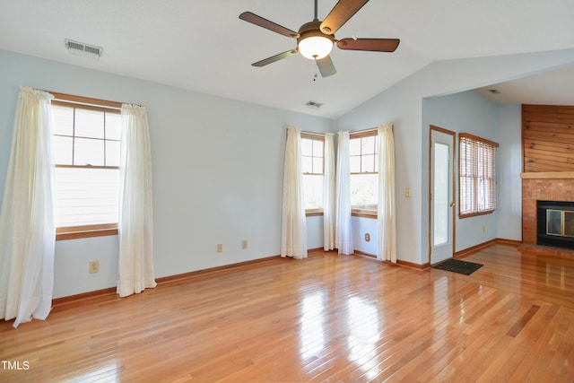 unfurnished living room featuring ceiling fan, lofted ceiling, a brick fireplace, and light wood-type flooring