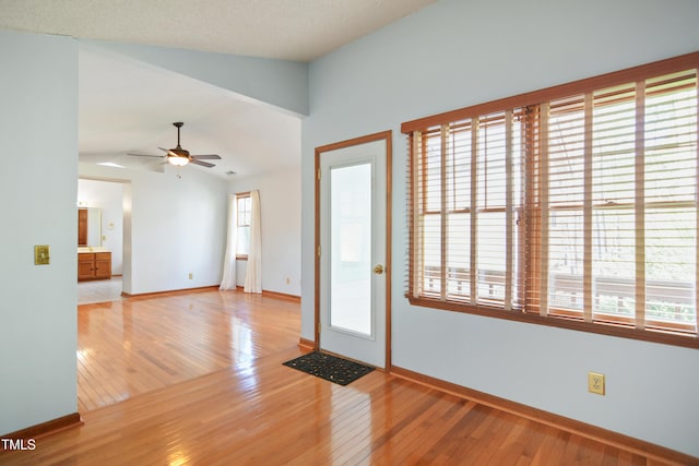 foyer entrance with lofted ceiling, ceiling fan, and light hardwood / wood-style flooring