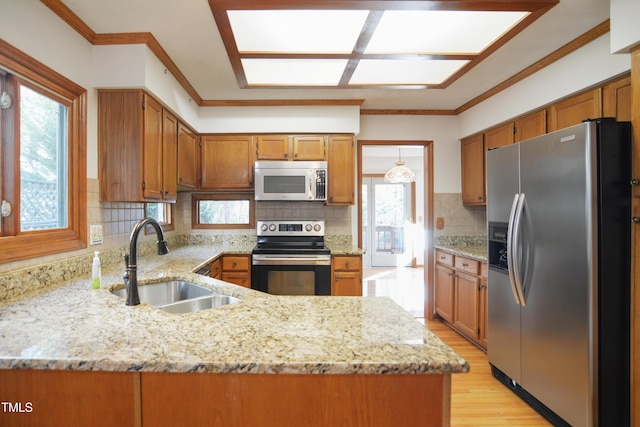 kitchen with ornamental molding, appliances with stainless steel finishes, sink, and kitchen peninsula