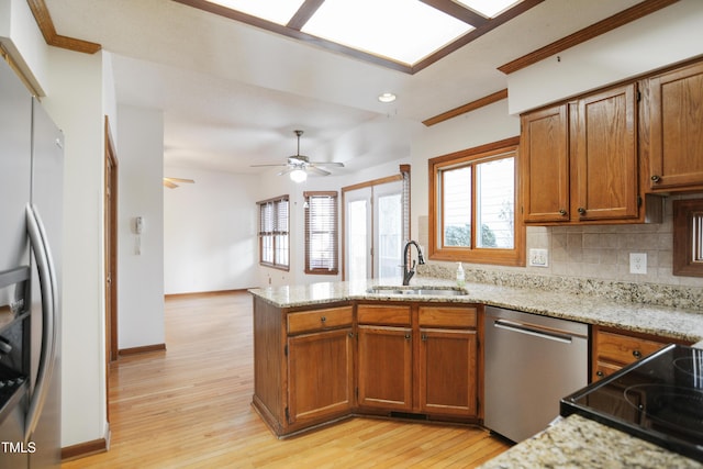 kitchen with appliances with stainless steel finishes, light hardwood / wood-style floors, sink, and decorative backsplash