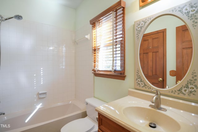 full bathroom featuring tiled shower / bath, vanity, and toilet