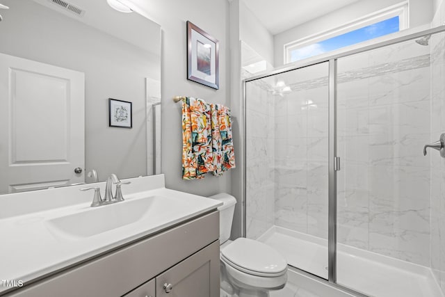 bathroom featuring toilet, a shower with door, and vanity