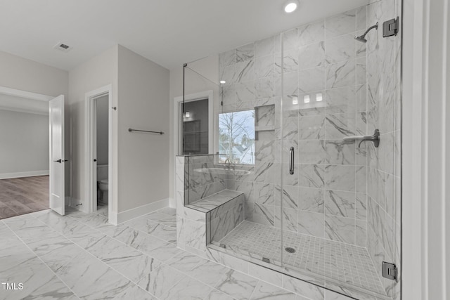 bathroom featuring a shower with shower door and toilet