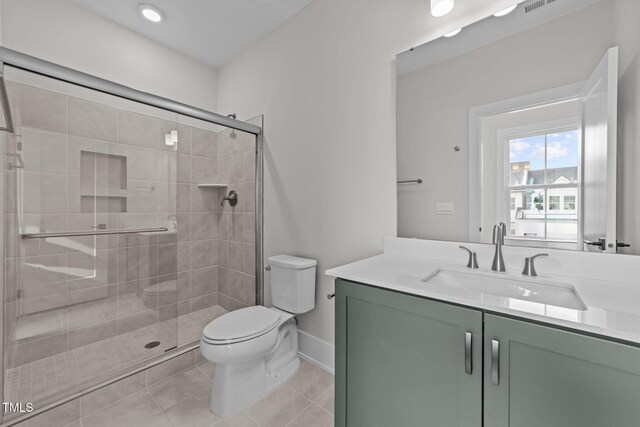 bathroom with tile patterned flooring, vanity, walk in shower, and toilet