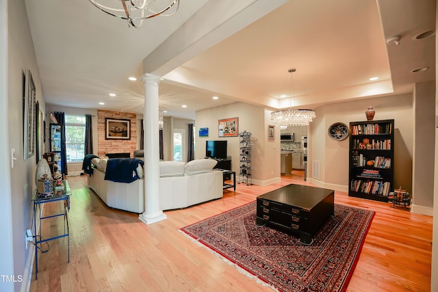 living room with ornate columns, a raised ceiling, hardwood / wood-style floors, and a fireplace