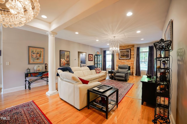 living room featuring decorative columns, a chandelier, and light hardwood / wood-style flooring