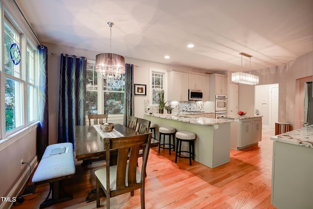 dining area featuring light wood-type flooring and a notable chandelier