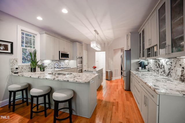 kitchen featuring stainless steel appliances, hanging light fixtures, sink, and kitchen peninsula