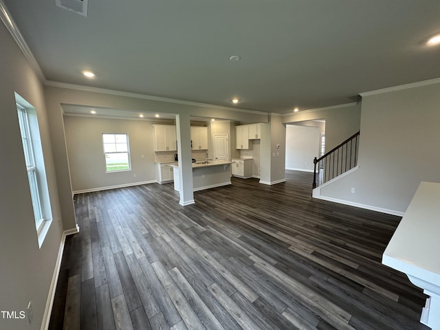 unfurnished living room featuring dark wood-type flooring and ornamental molding