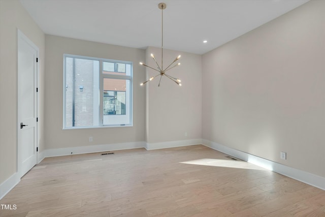 unfurnished dining area with a wealth of natural light, a notable chandelier, and light hardwood / wood-style flooring