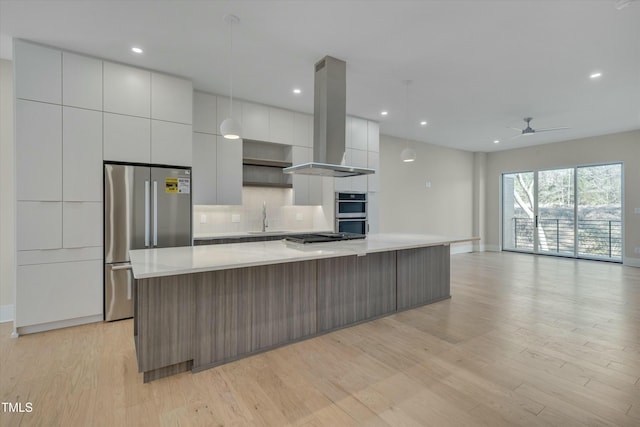 kitchen with a spacious island, tasteful backsplash, decorative light fixtures, appliances with stainless steel finishes, and island exhaust hood