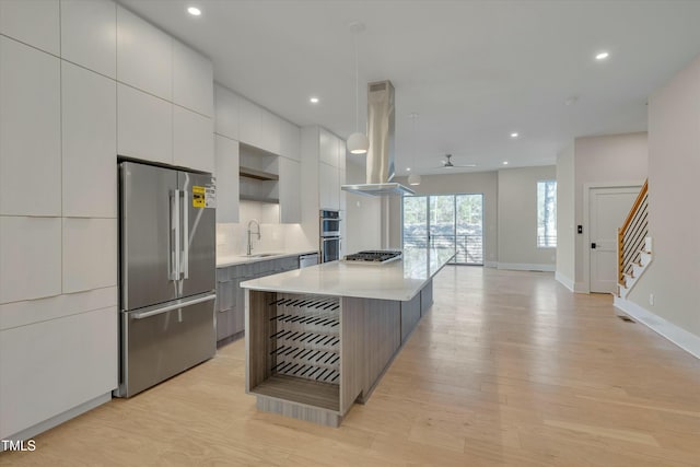 kitchen with island range hood, white cabinetry, sink, stainless steel appliances, and a spacious island