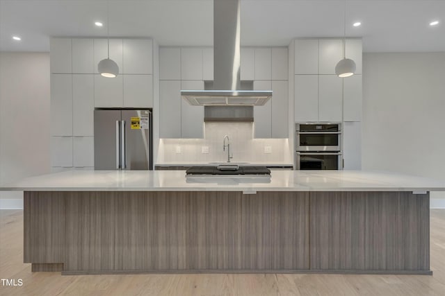 kitchen with a spacious island, light wood-type flooring, appliances with stainless steel finishes, island exhaust hood, and backsplash