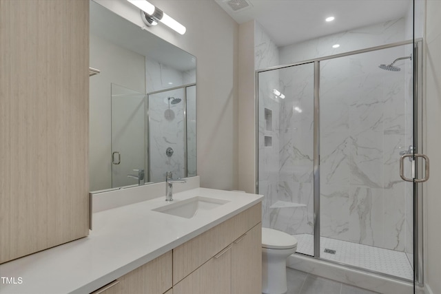 bathroom with tile patterned flooring, vanity, a shower with shower door, and toilet