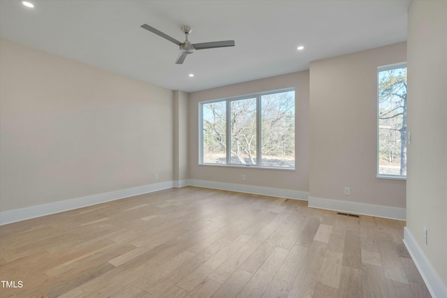 empty room with ceiling fan, plenty of natural light, and light wood-type flooring