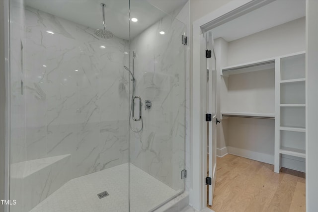 bathroom with a shower with door and hardwood / wood-style floors