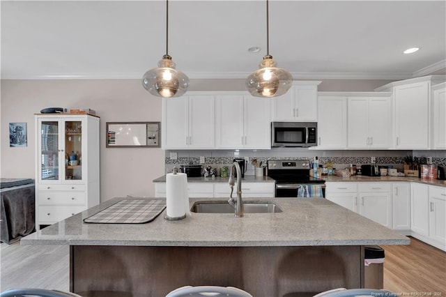 kitchen featuring an island with sink, sink, decorative backsplash, hanging light fixtures, and stainless steel appliances