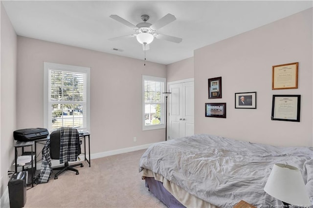 bedroom with ceiling fan, light colored carpet, and a closet