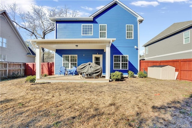 rear view of property with a storage unit, a patio, and a lawn