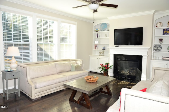 living room featuring dark hardwood / wood-style flooring, built in shelves, ornamental molding, and ceiling fan