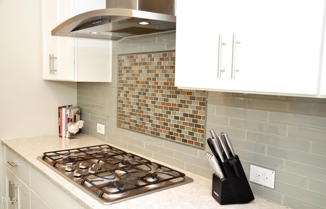 kitchen featuring decorative backsplash, stainless steel gas cooktop, white cabinets, and island exhaust hood