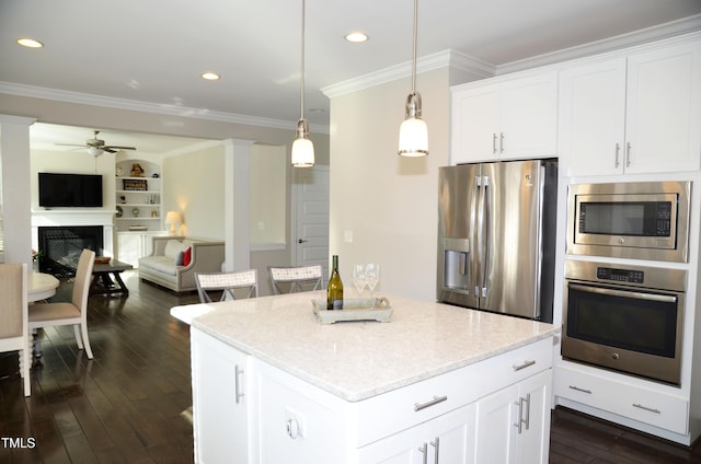 kitchen with pendant lighting, crown molding, appliances with stainless steel finishes, white cabinetry, and a kitchen island