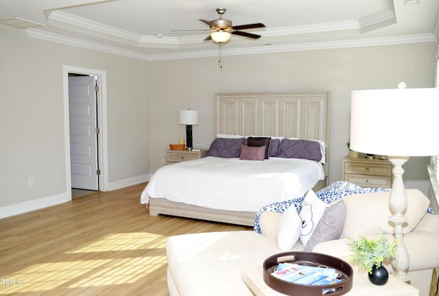 bedroom featuring ornamental molding, light hardwood / wood-style floors, ceiling fan, and a tray ceiling