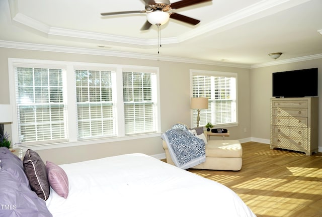 bedroom with a raised ceiling, ornamental molding, light wood-type flooring, and ceiling fan