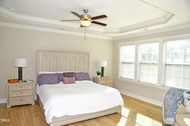 bedroom featuring crown molding, light wood-type flooring, ceiling fan, and a tray ceiling