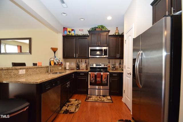 kitchen featuring sink, stainless steel appliances, light hardwood / wood-style floors, a kitchen bar, and kitchen peninsula