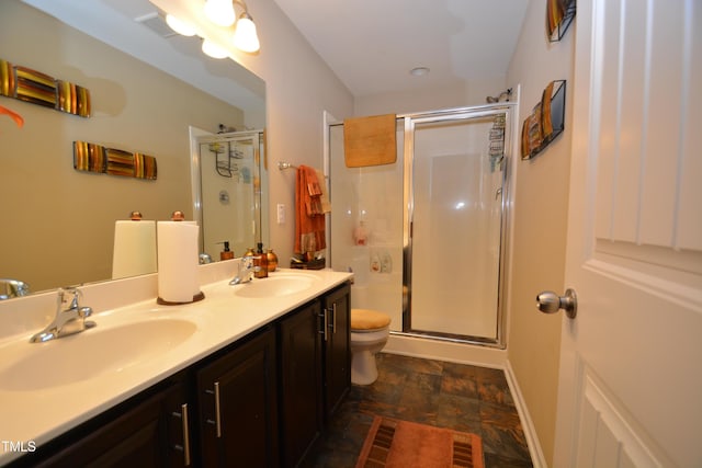 bathroom featuring toilet, vanity, and a shower with shower door