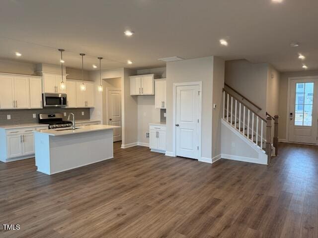 kitchen with white cabinetry, decorative light fixtures, an island with sink, and appliances with stainless steel finishes