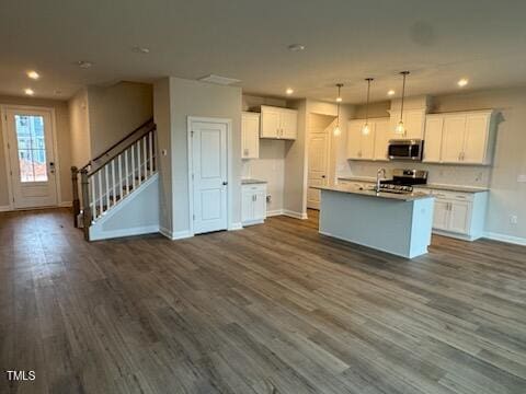 kitchen featuring appliances with stainless steel finishes, a center island with sink, and white cabinets