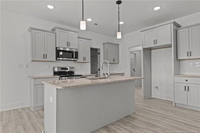 142 Peeler Cir, Raeford, NC 28376 - kitchen with appliances with stainless steel finishes, gray cabinetry, light wood-style flooring, a center island with sink, and decorative light fixtures