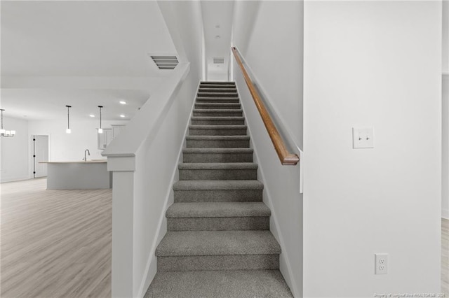 142 Peeler Cir, Raeford, NC 28376 - stairs featuring wood finished floors, a chandelier, and recessed lighting
