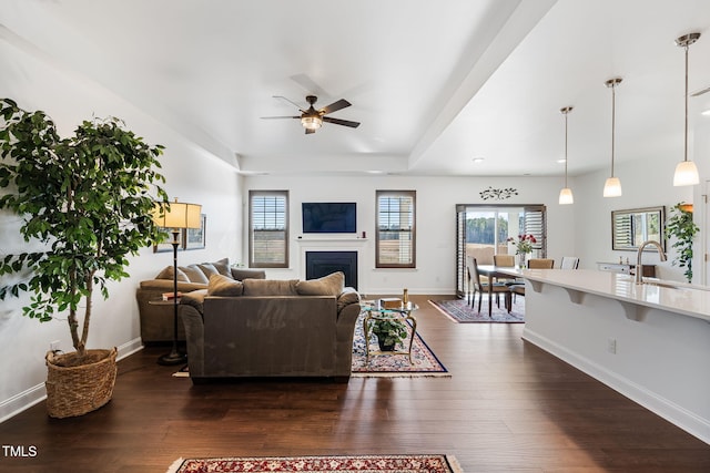 living room featuring dark wood-type flooring, ceiling fan, and sink