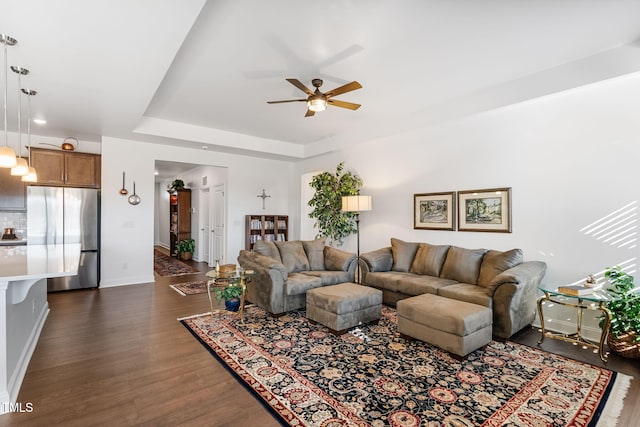 living room featuring ceiling fan, dark hardwood / wood-style flooring, and a raised ceiling